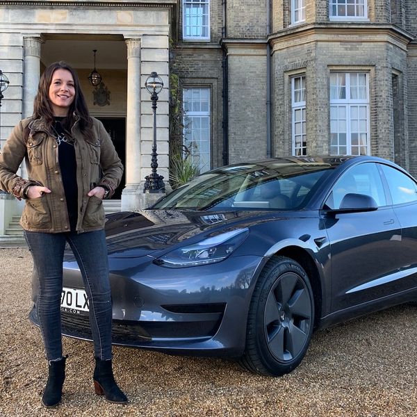 Ginny Buckley with a Tesla Model 3 in front of posh house